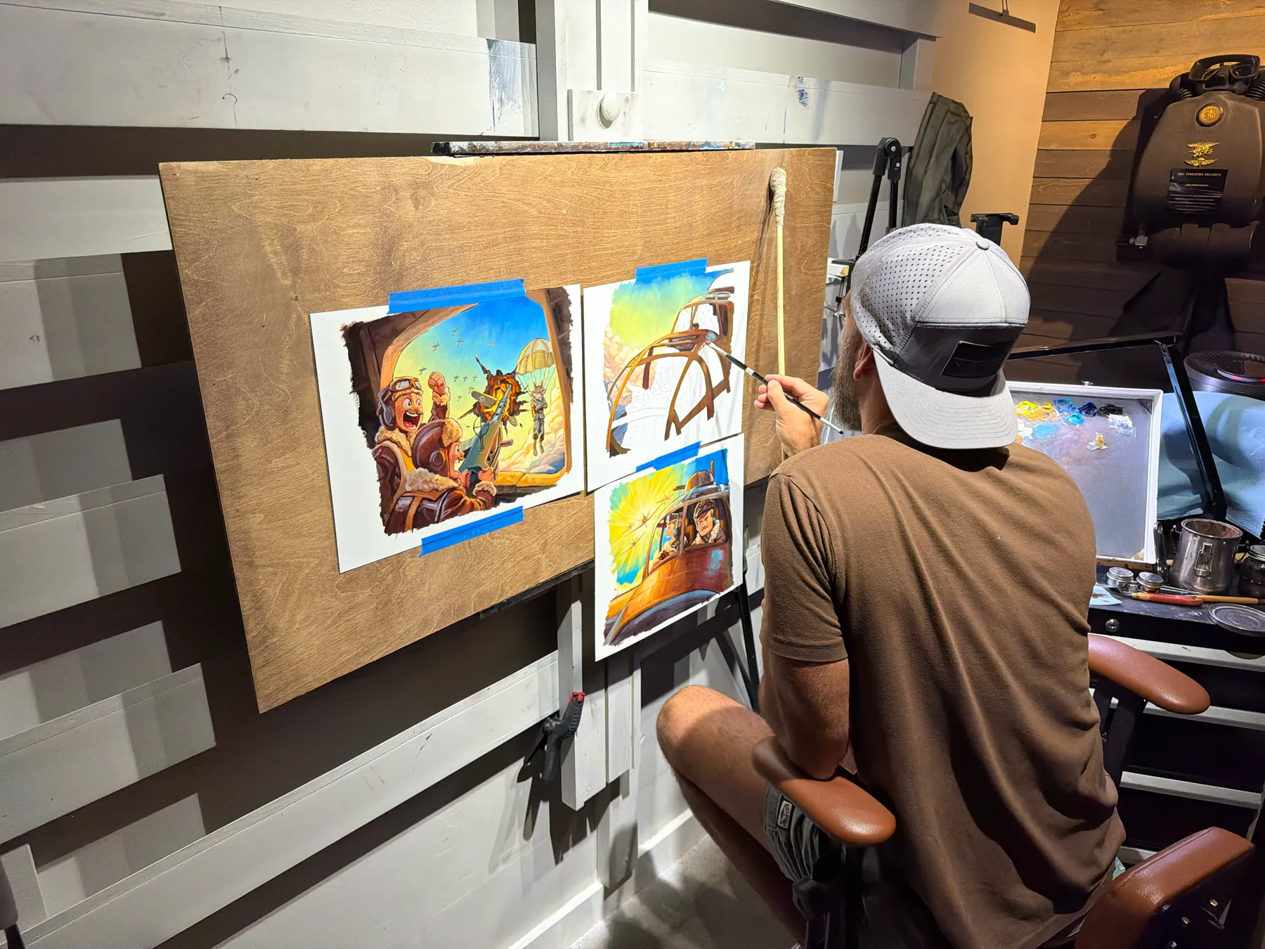Justin Hughes painting a Bomber Boys illustration at his easel