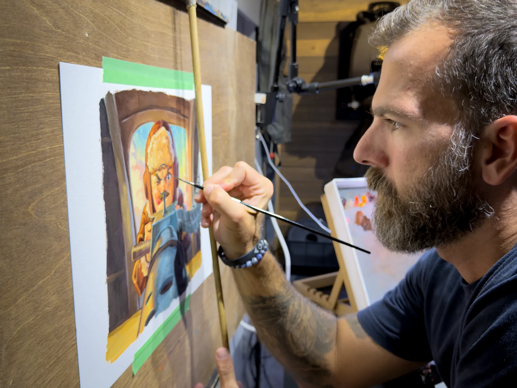Justin Hughes at work on three Bomber Boys paintings taped to a board